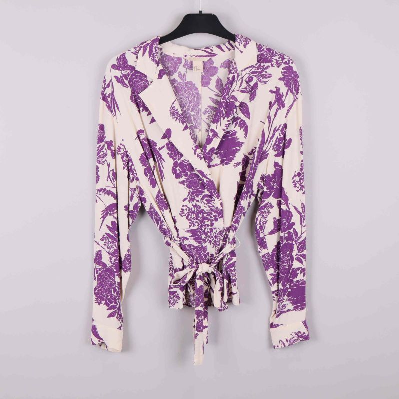 Framsidan av blommig omlottblus med knytband och lila mönster