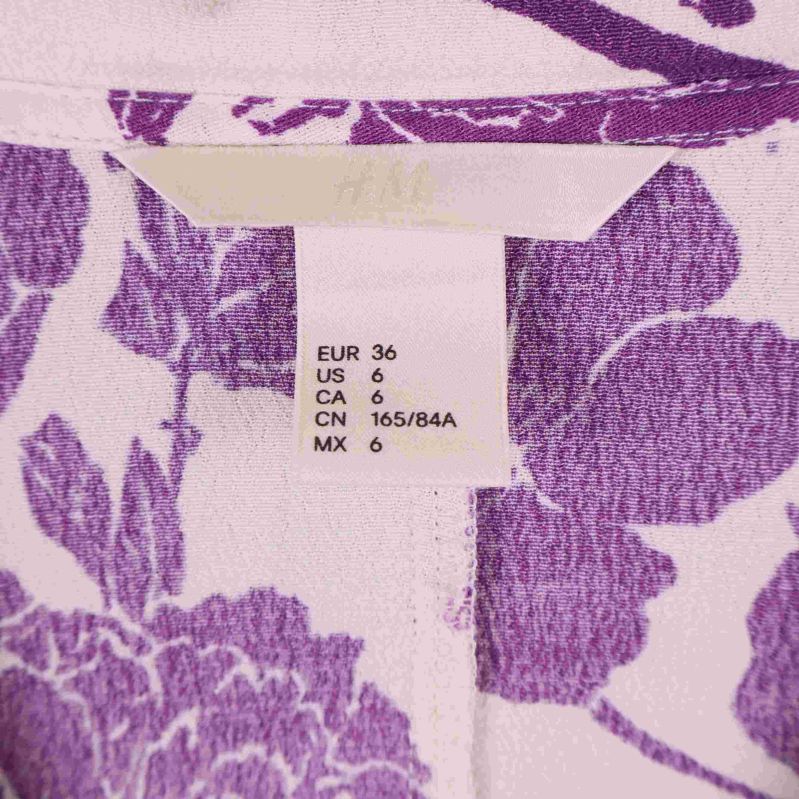 Storleksetikett EUR 36 på blommig lila och vit blus