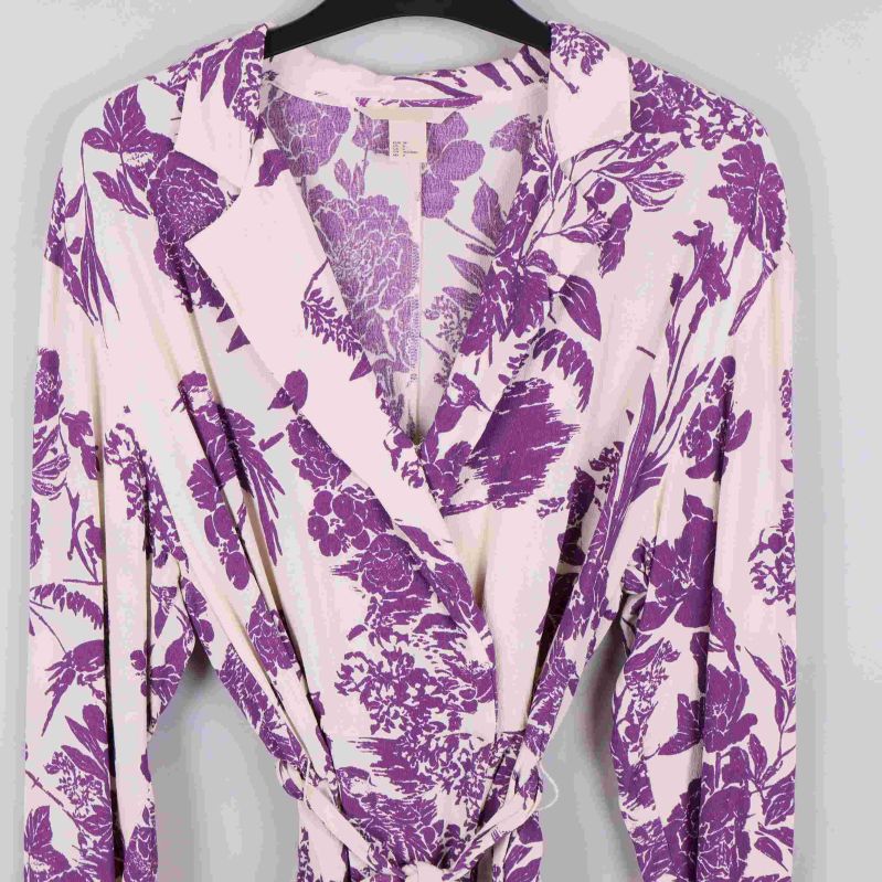 Närbild på omlottblusens krage och överdel med lila blommönster