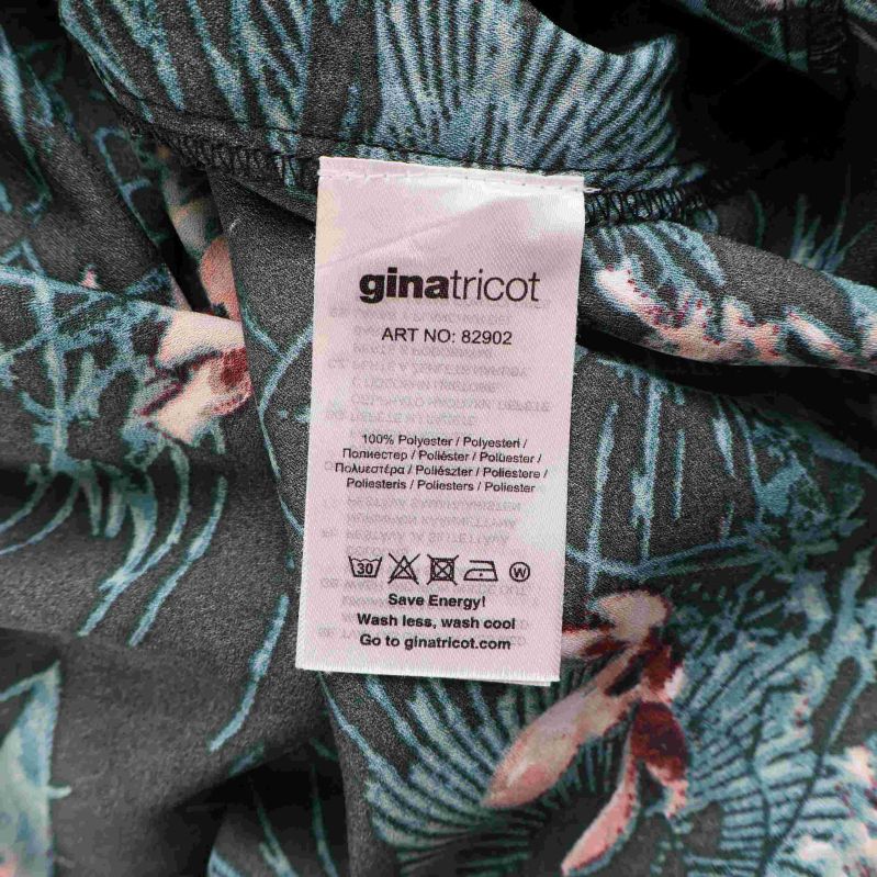 Materialetikett som visar 100% polyester på blommig klänning