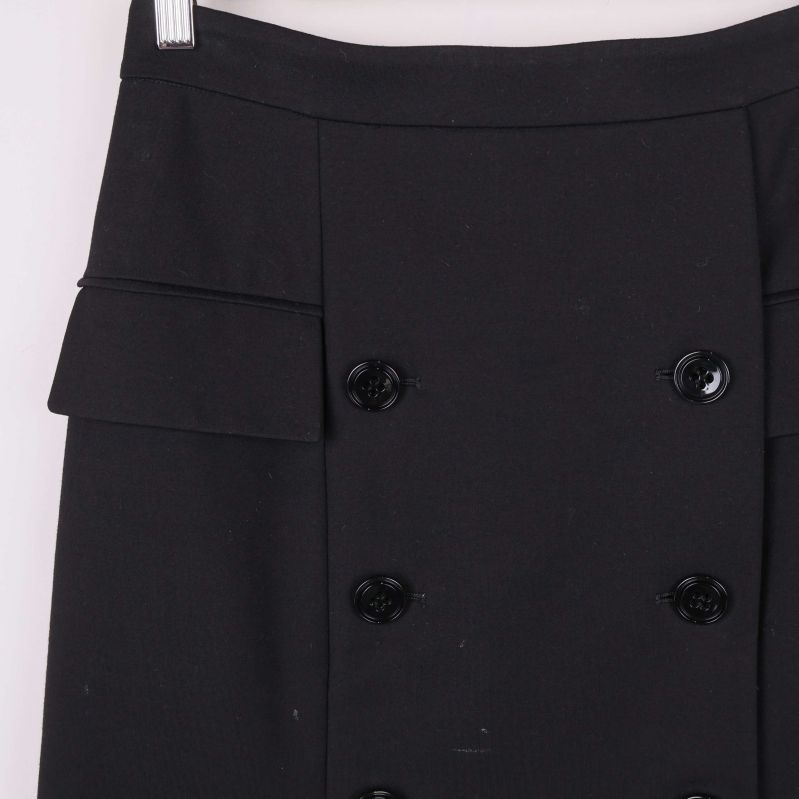 Närbild på fickdetalj och knappar på svart kjol