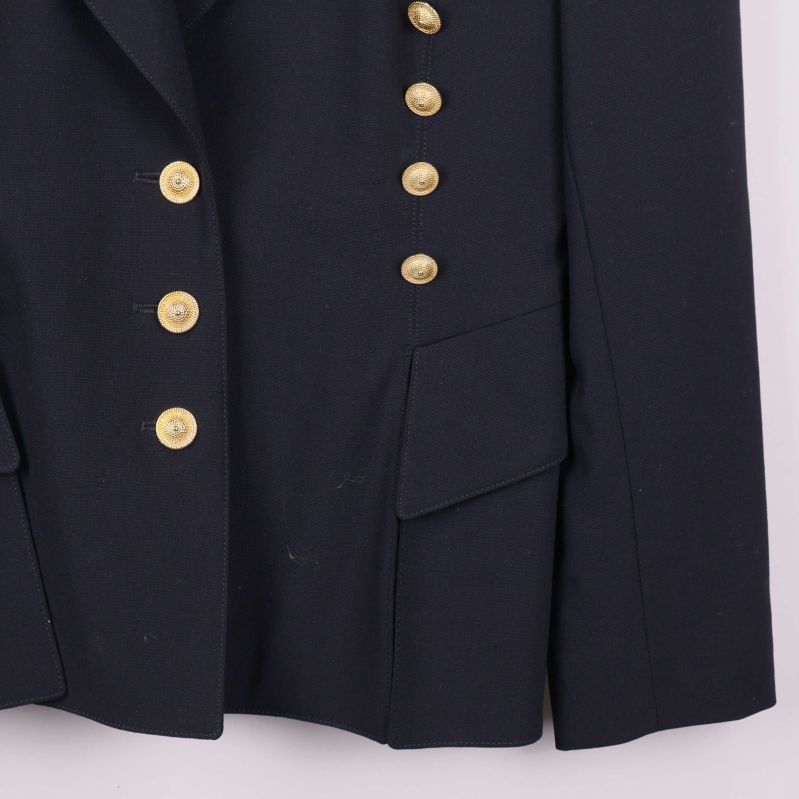 Nedre högra fickan och guldknappar på kavajen i närbild