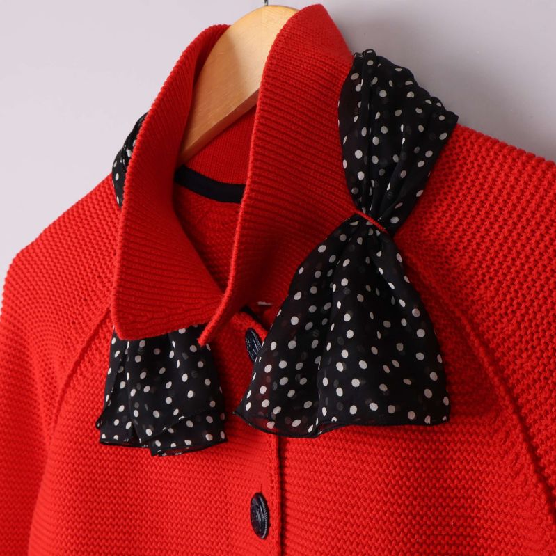 Närbild svartprickig krage mot röd stickad kofta
