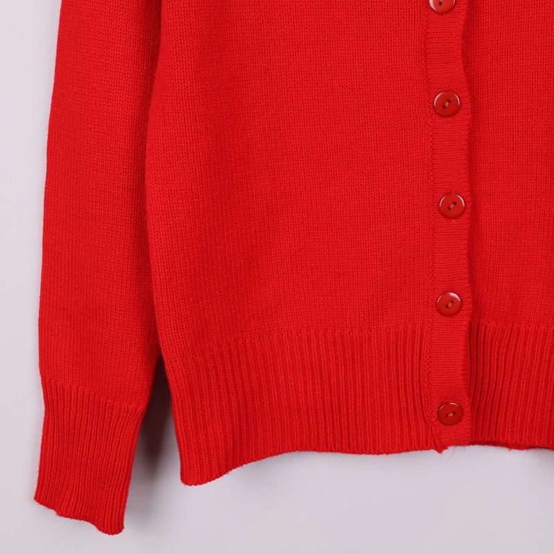Ärm och nederkant på röd stickad kofta med ribbade detaljer