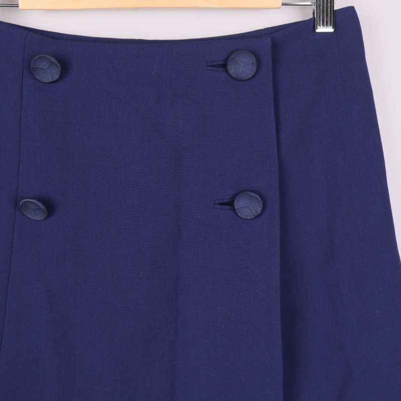 Närbild på dubbla knappar framtill på mörkblå kjol