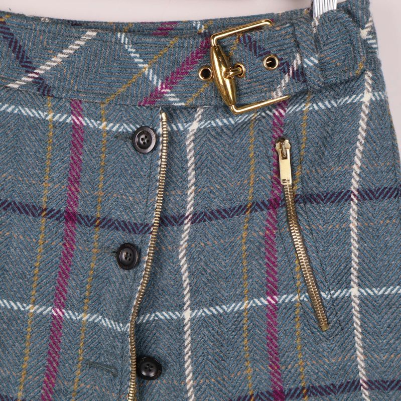 Närbild på kjolens blixtlås, knappar och guldfärgat bälte