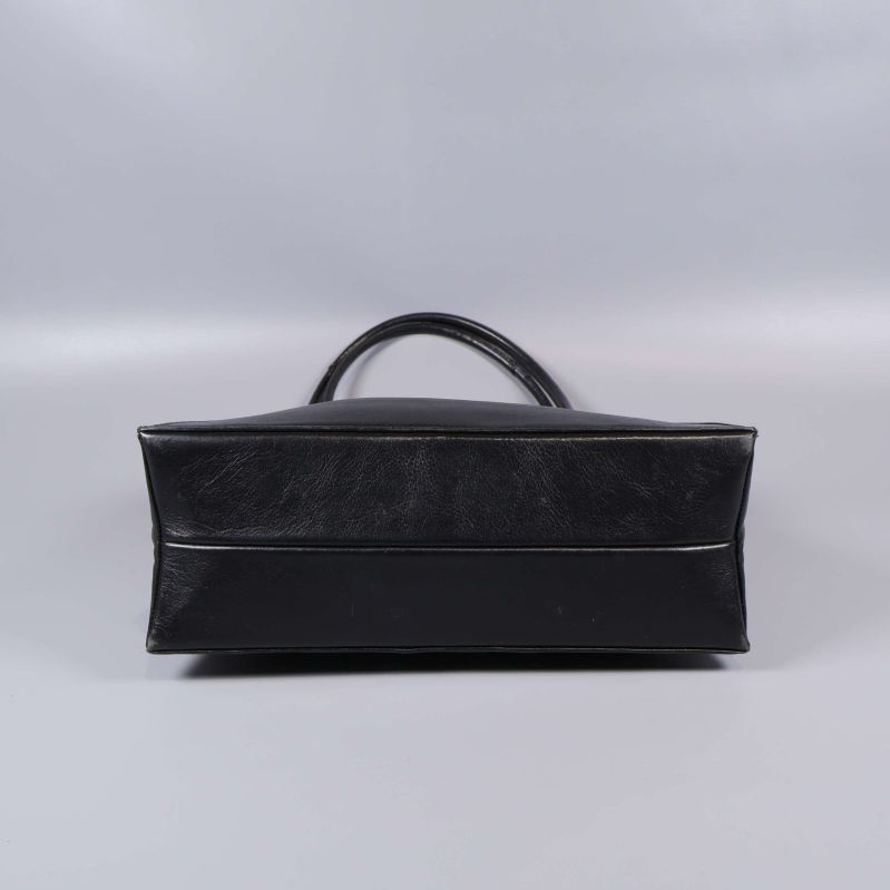 Botten av svart läderväska visas liggande