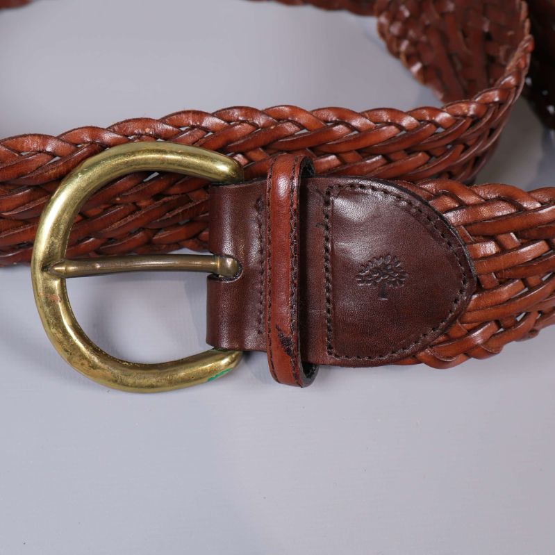 Närbild på prägling och spänne på flätat bälte