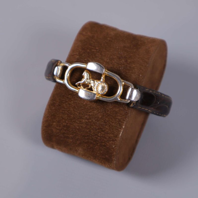 Närbild på armbandets guldfärgade logo