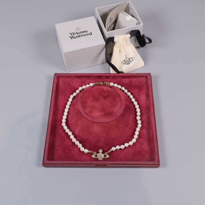 Pärlhalsband med gulddetalj i öppnad ask