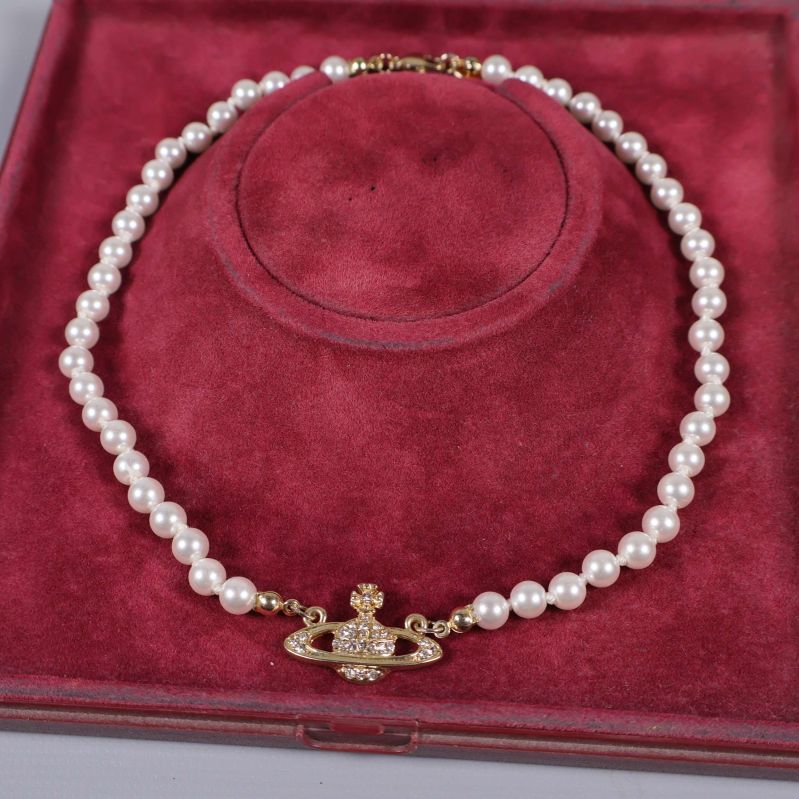 Närbild på pärlhalsbandet med guldfärgad emblem
