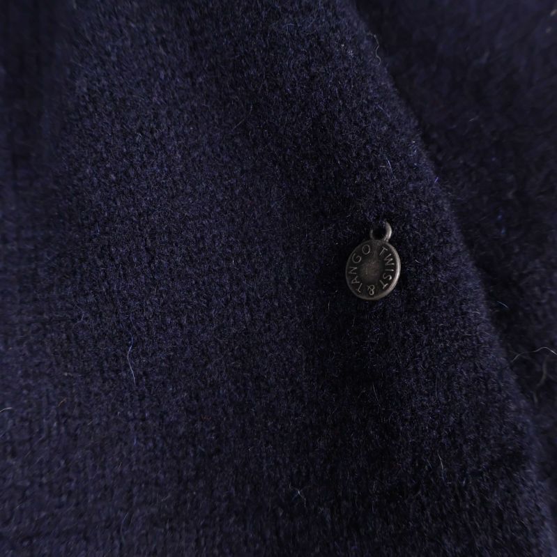 Närbild på metallbricka på mörkblått trikåtyg