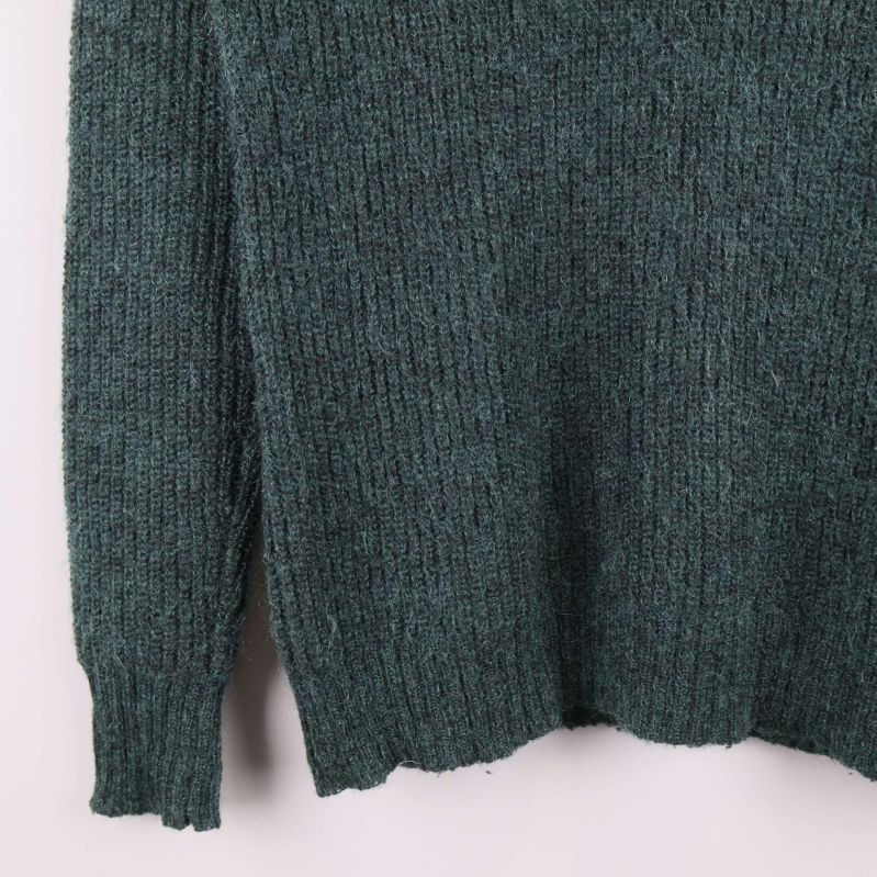 Närbild på nederkant och ärmslut på stickad tröja