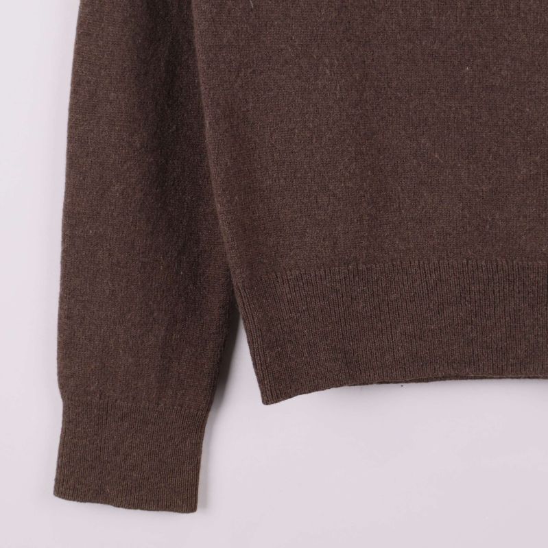 Stickad mudd och nederkant på brun tröja i närbild