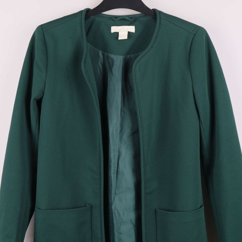 Närbild framtill på grön jacka med två fickor