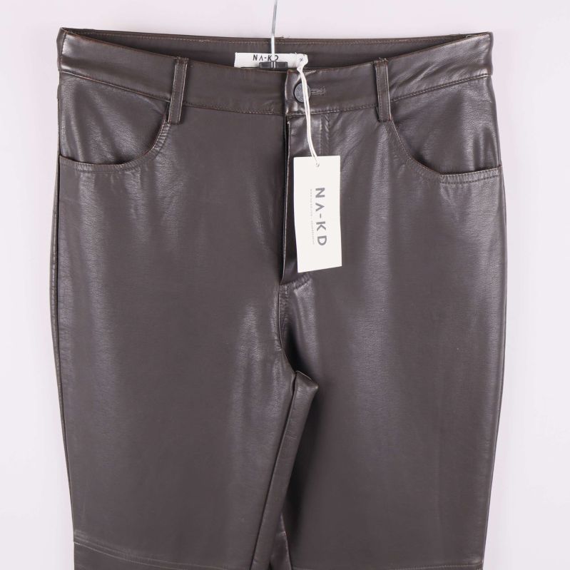 Närbild överdel på konstläderbyxor med namnlapp och knapp