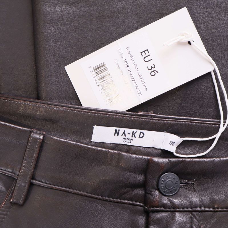 Storlekslapp och NA-KD varumärke på brun byxa