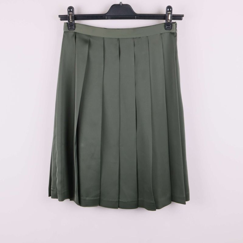 Grön plisserad kjol framifrån på galge