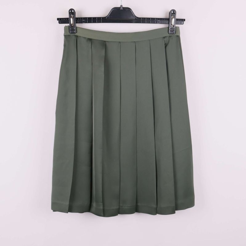 Grön plisserad kjol bakifrån på galge