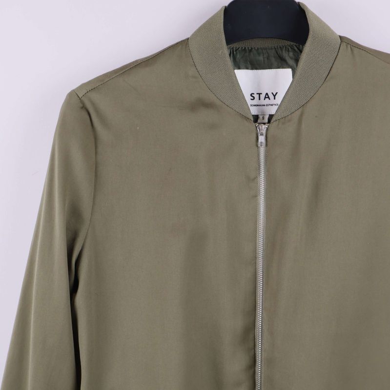 Närbild på halsringning och dragkedja i olivgrönt tyg