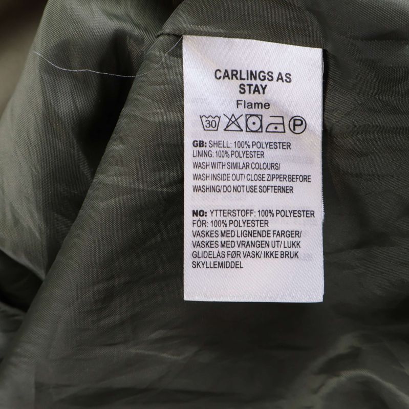 Materialetikett som anger 100% polyester på jackans foder och yttertyg