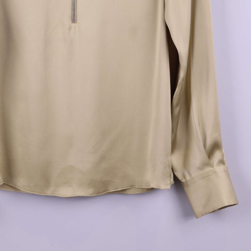 Detaljbild nedre delen av beige blus med fåll och manschett