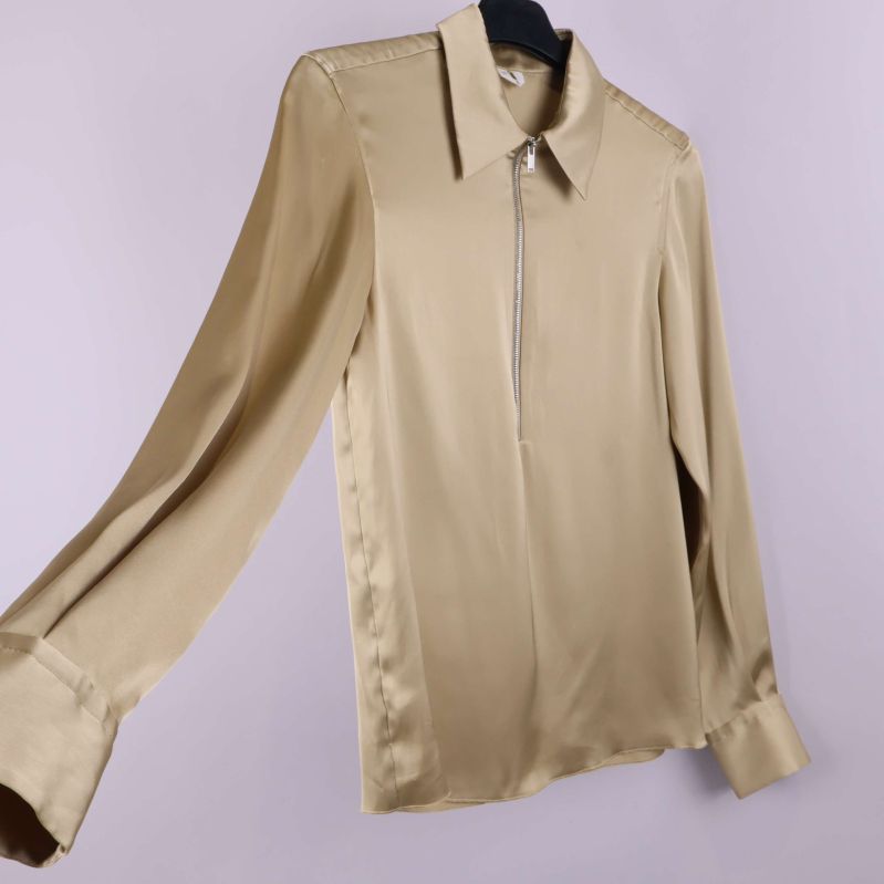 Beige blus visad i vinkel med långa ärmar