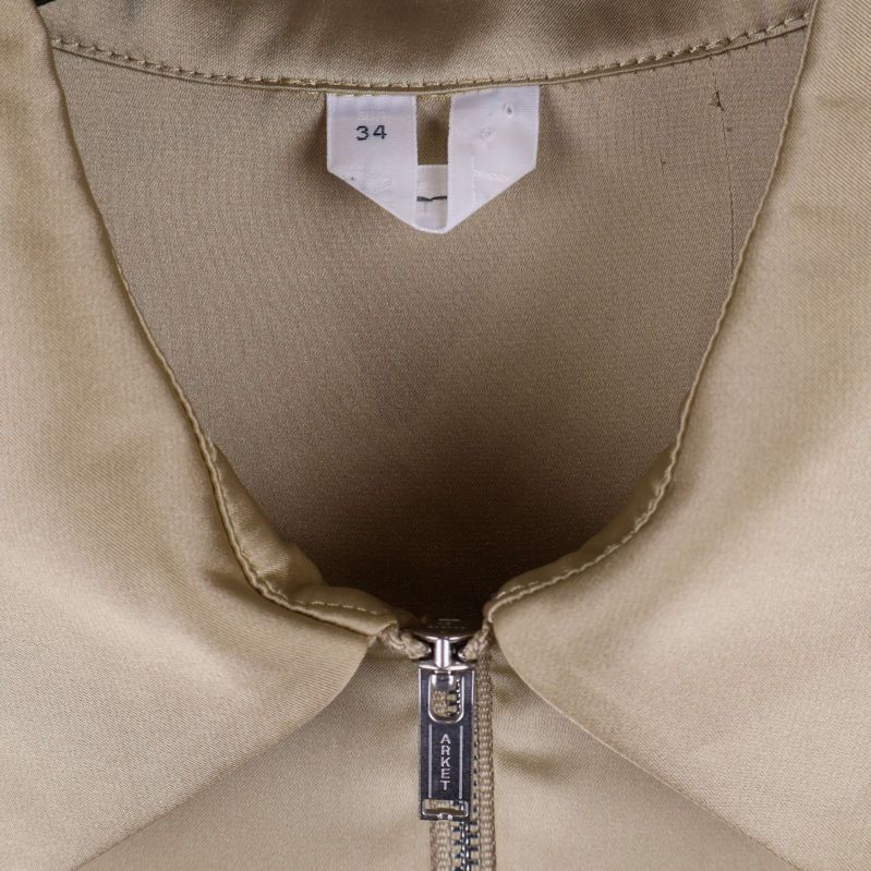 Närbild på krage och storlekslapp 34 på beige blus