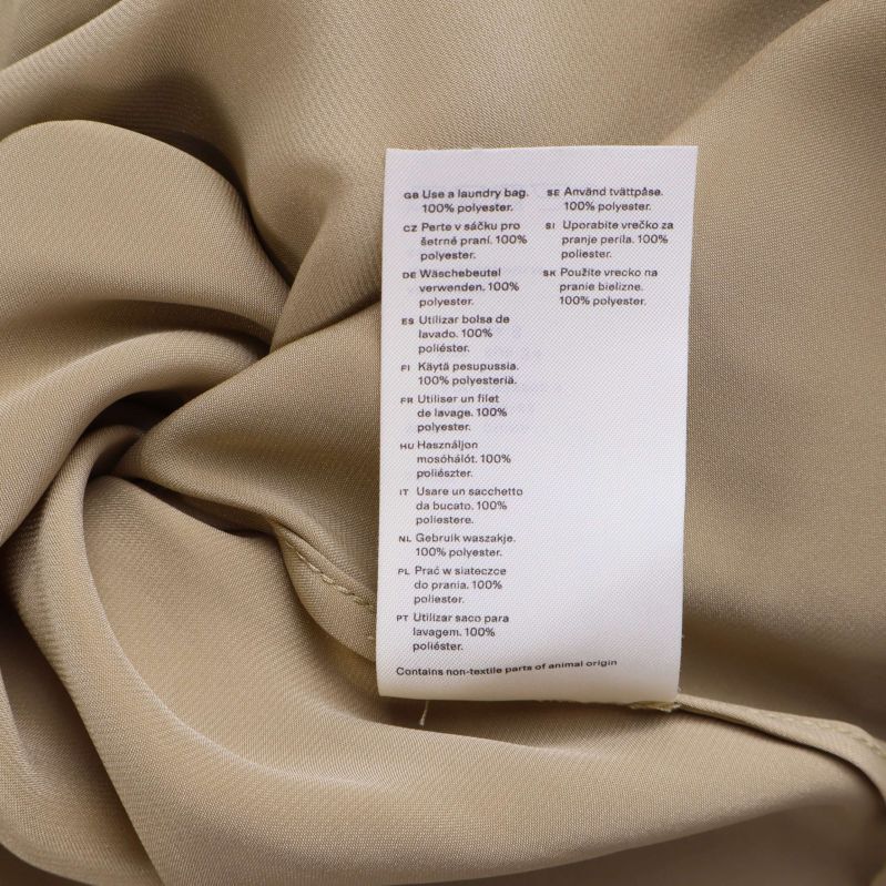 Materiallapp som visar 100% polyester på beige tyg