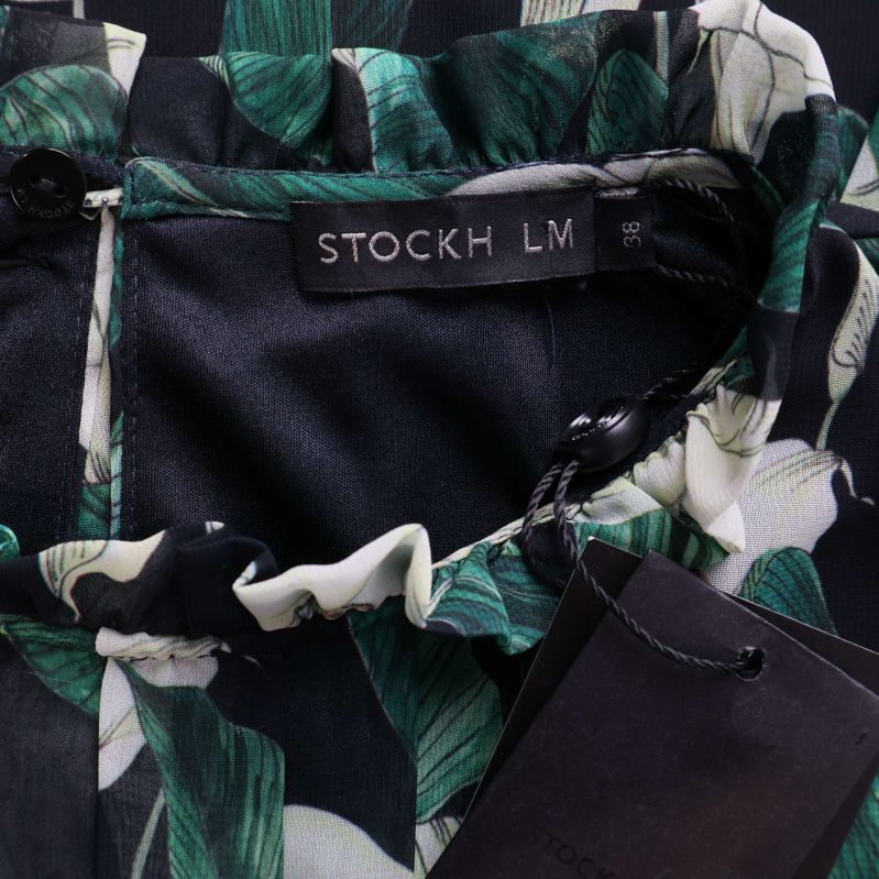 Närbild etikett STOCKH LM i blommig klänning