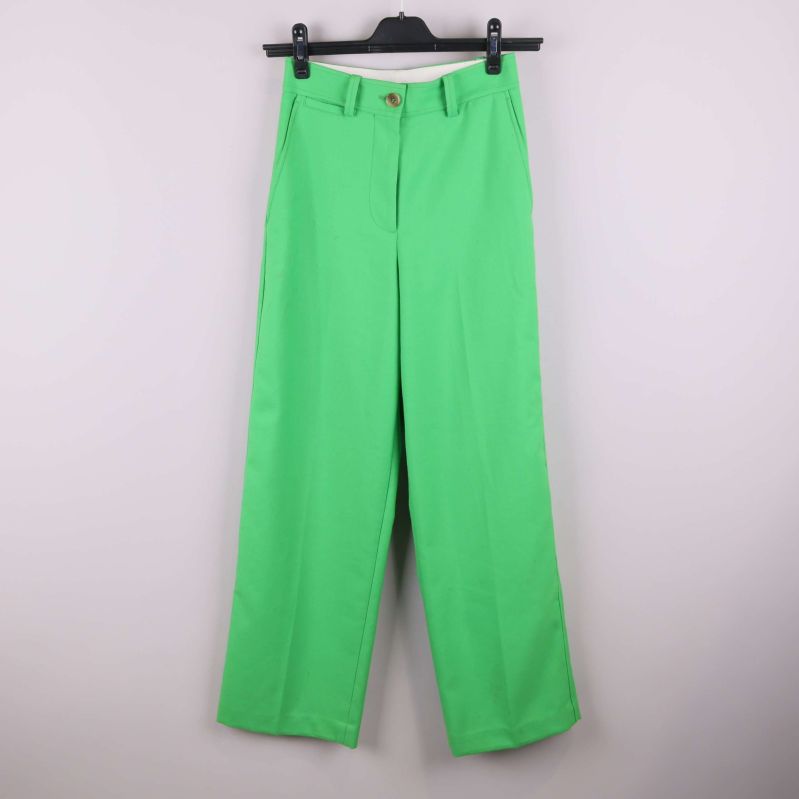 Gröna raka byxor hängande på galge mot ljus bakgrund