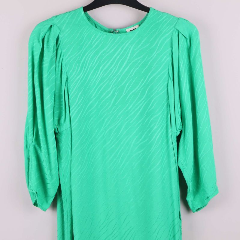 Överkroppsdetalj av grön klänning med struktur