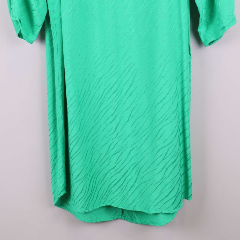 Nederkant på grön klänning med struktur