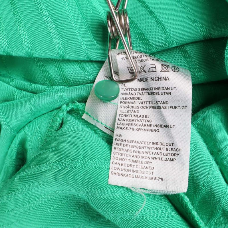 Tvättlapp med materialinformation i grön klänning