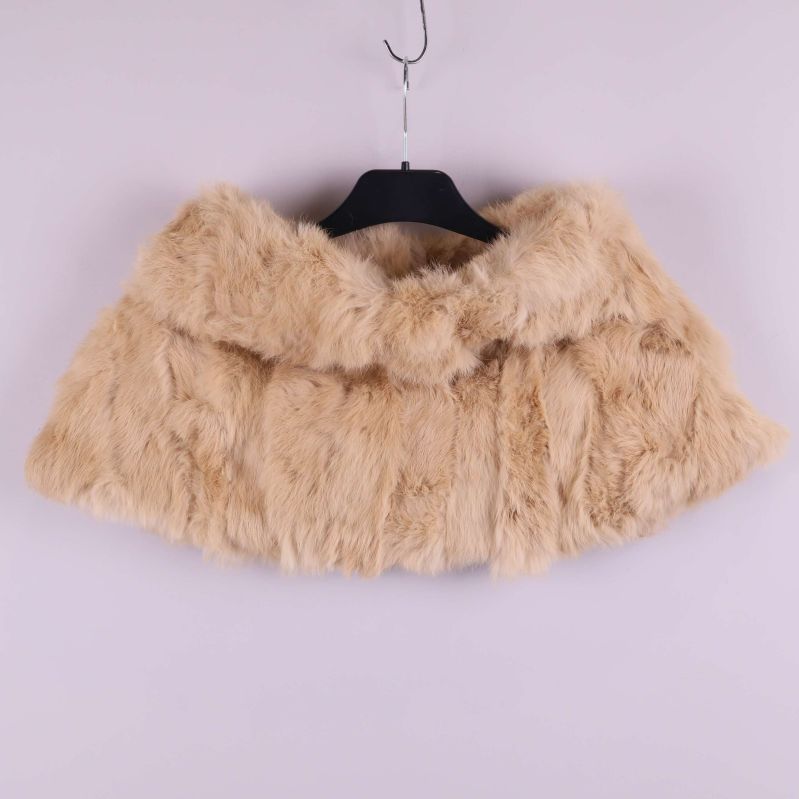 Beige pälsponcho på galge med fluffig textur och krage