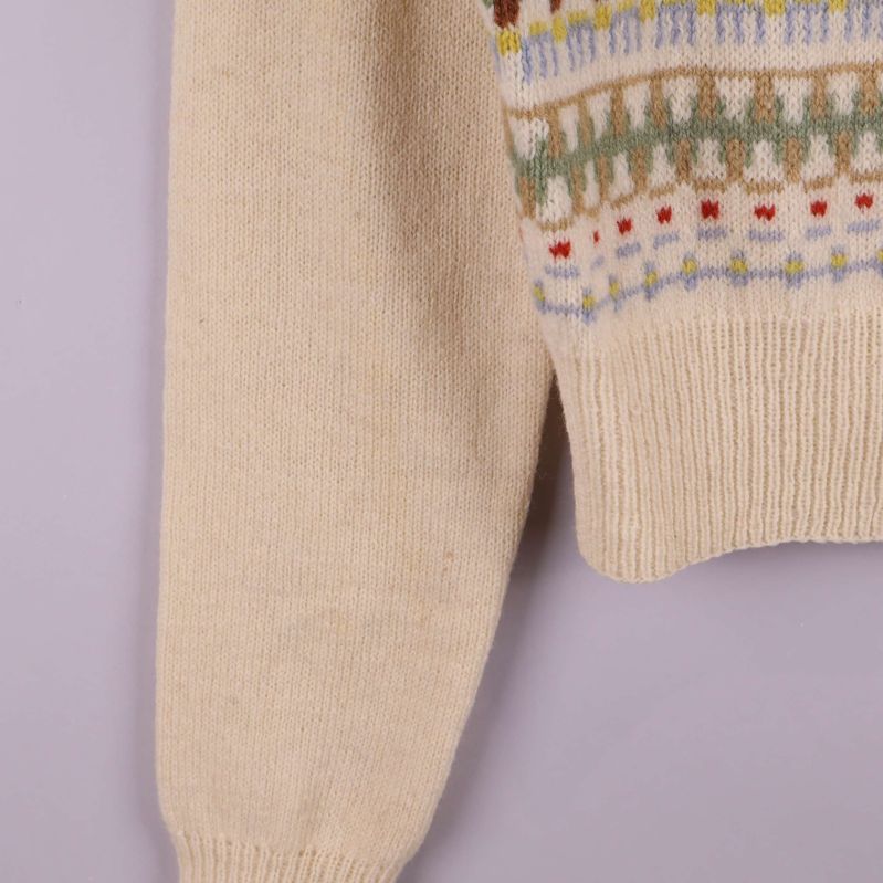 Närbild på höger ärm och nederkant av mönstrad kofta