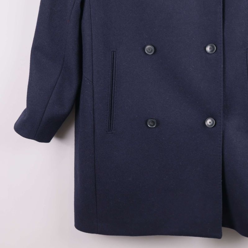 Närbild på kappans fickor och knappar nertill