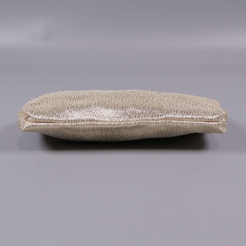 Botten på clutch i guldig färg mot grå bakgrund