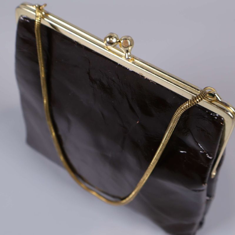 Närbild guldig ram på brun väska