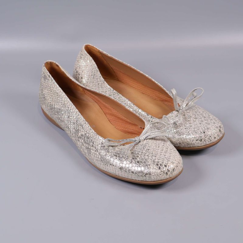 Ett par ballerinaskor med metallisk yta och rosett