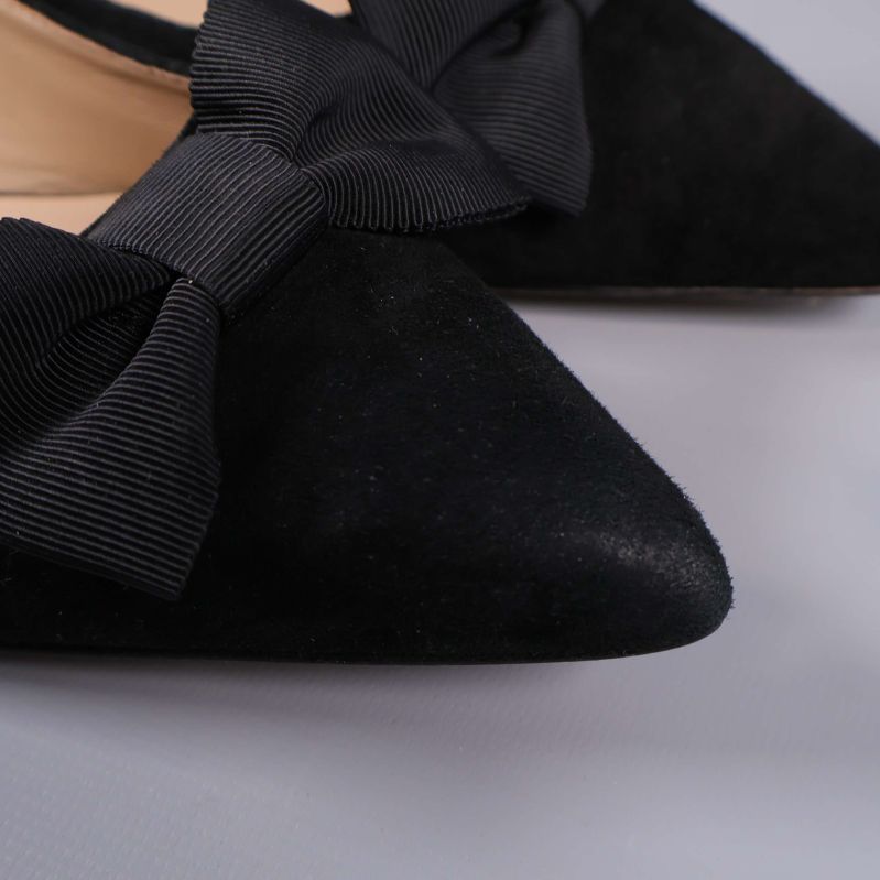 Närbild på svart ballerinasko med rosett och mockastruktur