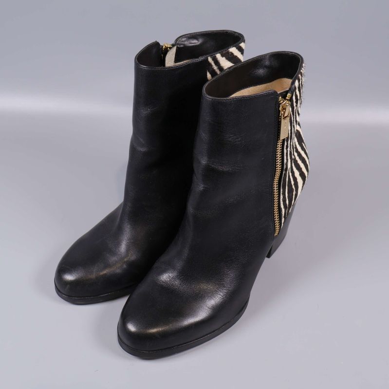 Överifrån syns svarta boots med zebramönstrad kant och dragkedja