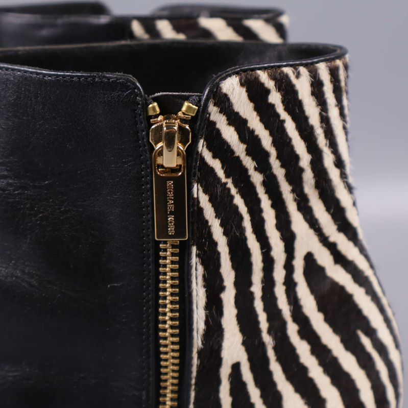 Närbild på dragkedja med Michael Kors präglad text och zebramönster