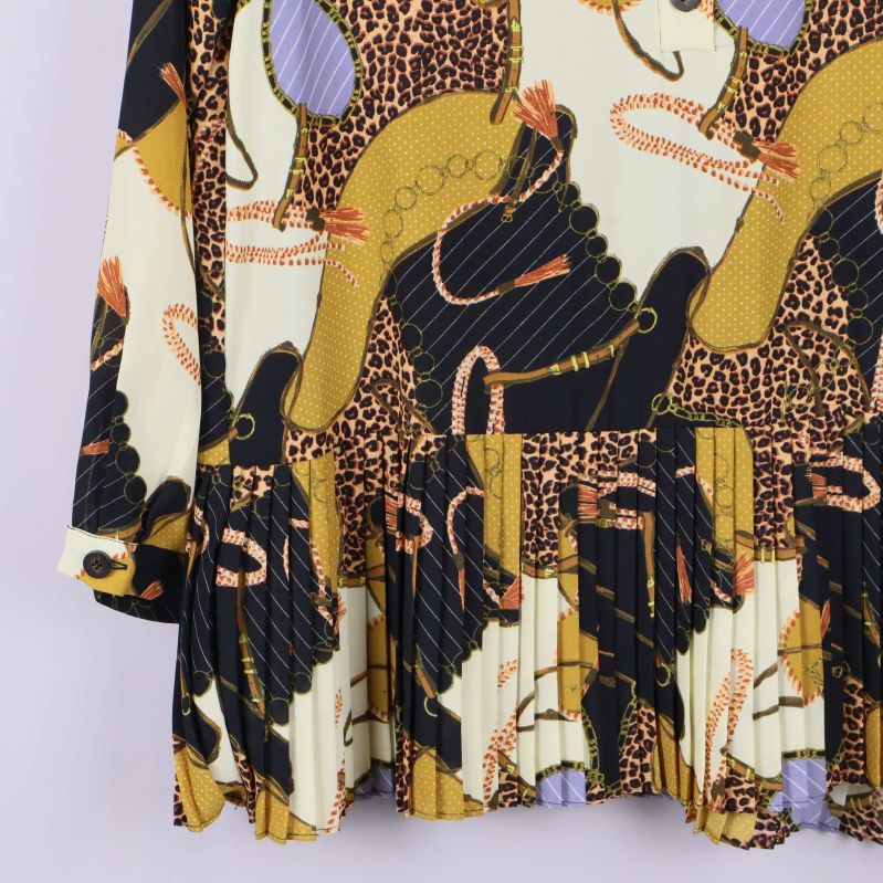 Närbild på tunikans plisserade nederkant och ärmslut