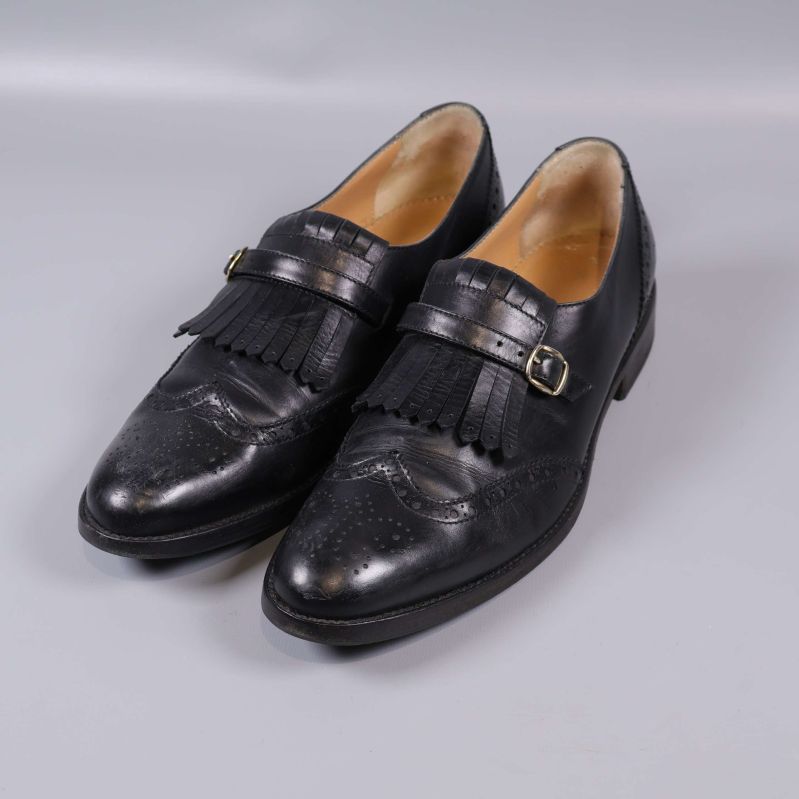 Par svarta loafers med frans och spänne sedd snett framifrån