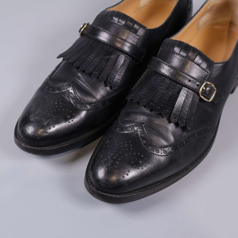 Närbild på skon med broguemönster, fransdetalj och spänne