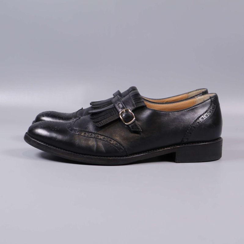 Svarta loafers sedd från andra sidan med spänne och frans