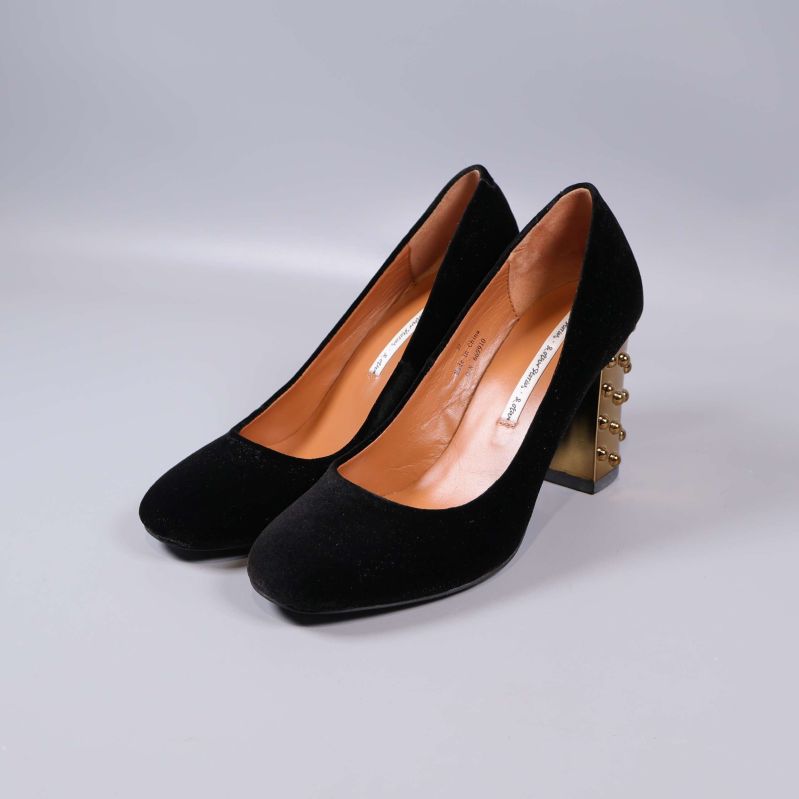 Paret svarta pumps med metalliska klackar i vinkel