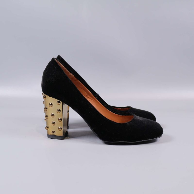 Profil av svart pump med guldfärgad klack och nitar