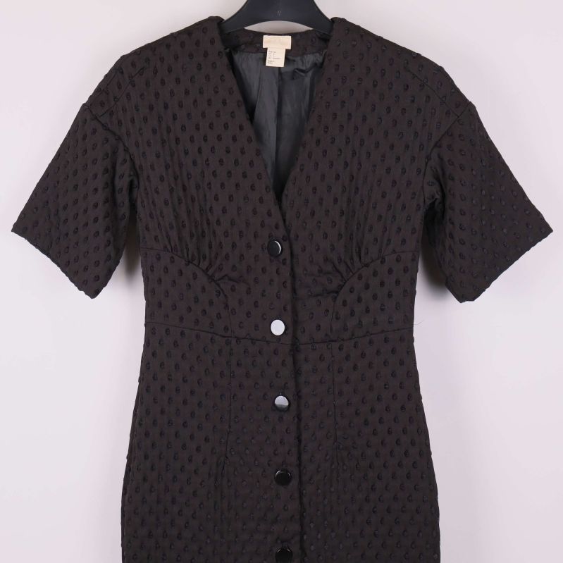 Närbild på kort svart klänning, överdel med knappar